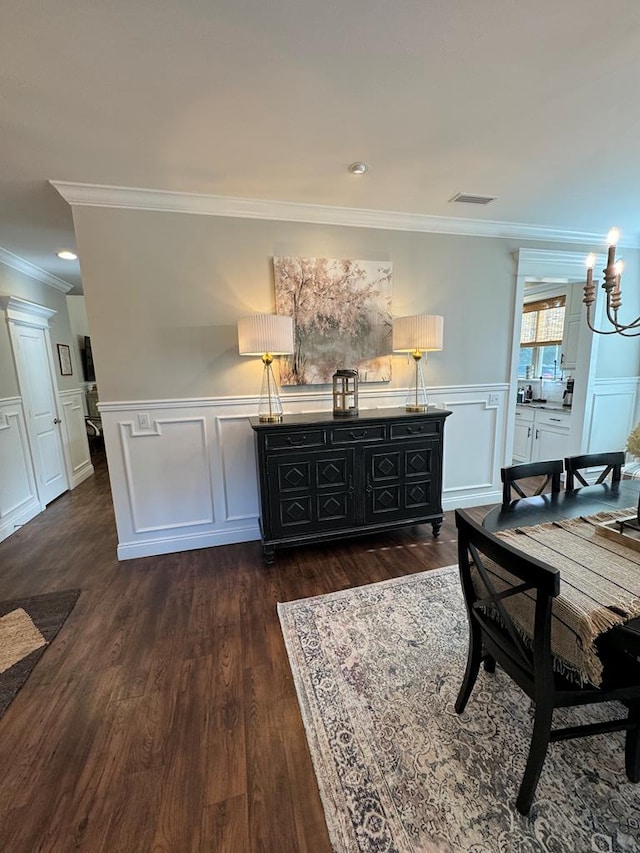 dining room with a decorative wall, crown molding, dark wood-style flooring, and a wainscoted wall