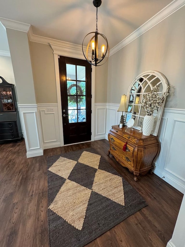 entrance foyer with crown molding, wood finished floors, a chandelier, and a decorative wall