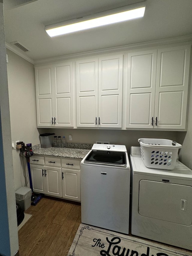 clothes washing area with dark wood-style floors, visible vents, independent washer and dryer, crown molding, and cabinet space
