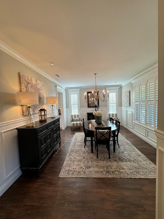 dining area featuring a decorative wall, crown molding, a healthy amount of sunlight, and an inviting chandelier
