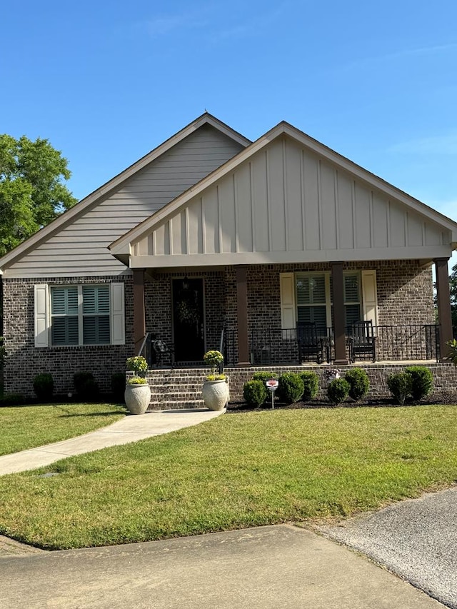 view of front of house featuring brick siding, a porch, and a front lawn