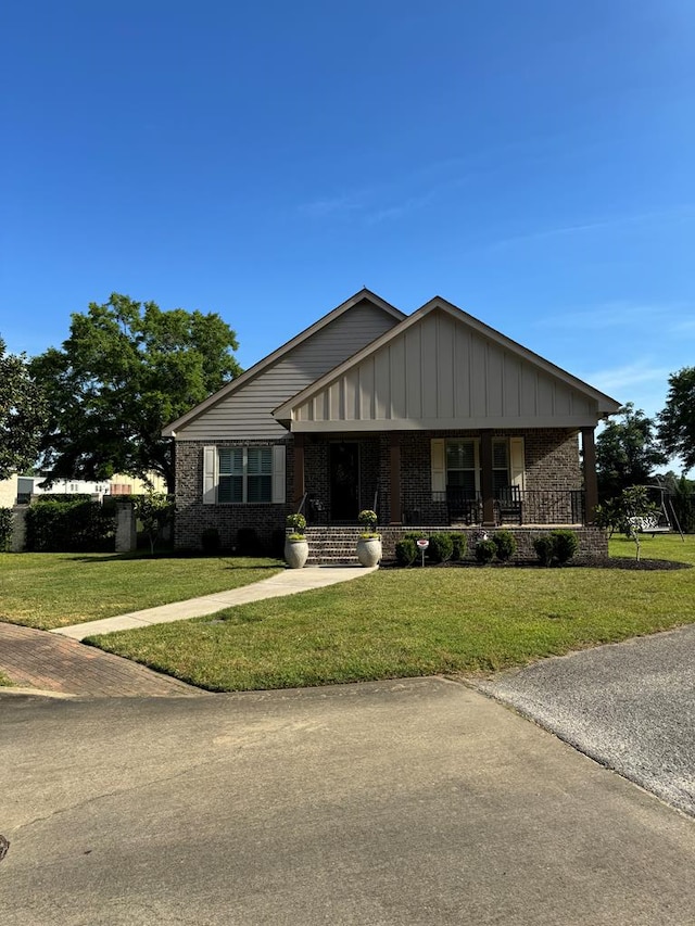 view of front of home featuring brick siding, a front yard, and covered porch