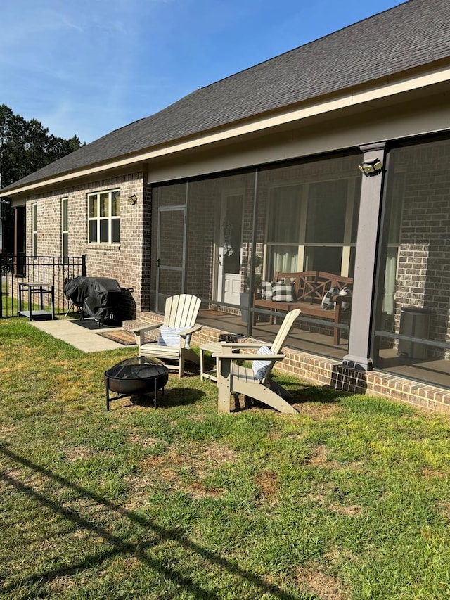 back of property featuring fence, a patio, a lawn, an outdoor fire pit, and brick siding