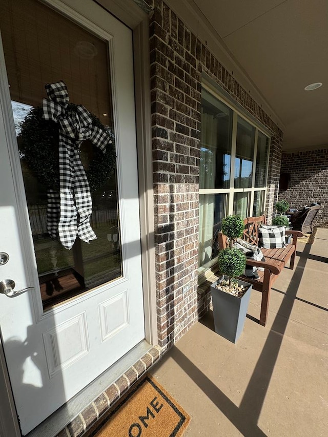 view of exterior entry featuring brick siding and covered porch