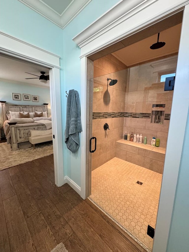 ensuite bathroom featuring a shower stall, hardwood / wood-style flooring, ornamental molding, and ensuite bathroom