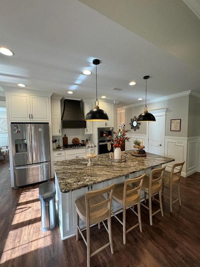 kitchen with dark wood-type flooring, crown molding, appliances with stainless steel finishes, white cabinetry, and custom range hood