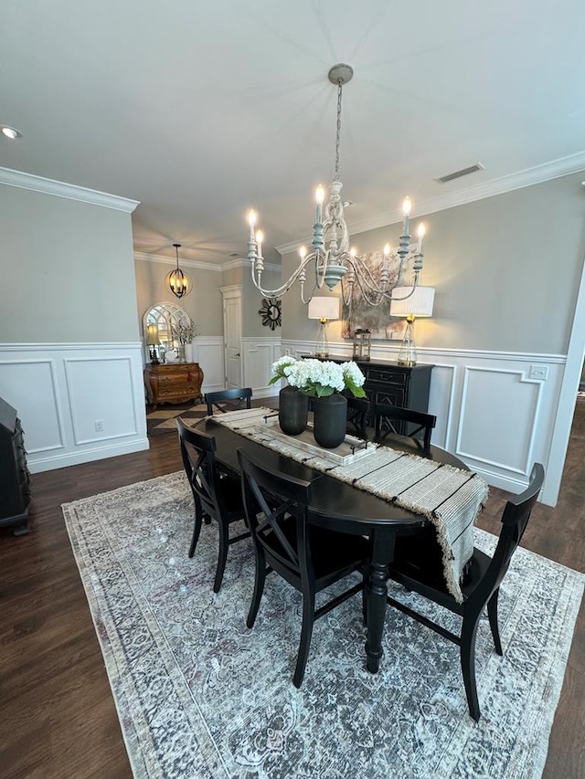 dining room with an inviting chandelier, ornamental molding, dark wood-style flooring, and visible vents