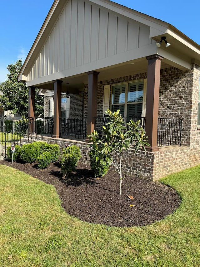 exterior space featuring a lawn, fence, board and batten siding, and brick siding