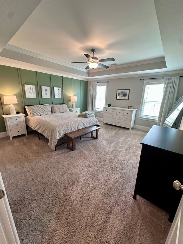 carpeted bedroom featuring crown molding, a tray ceiling, and multiple windows