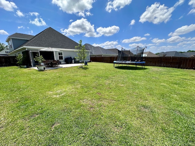 view of yard with a fenced backyard, a trampoline, and a patio