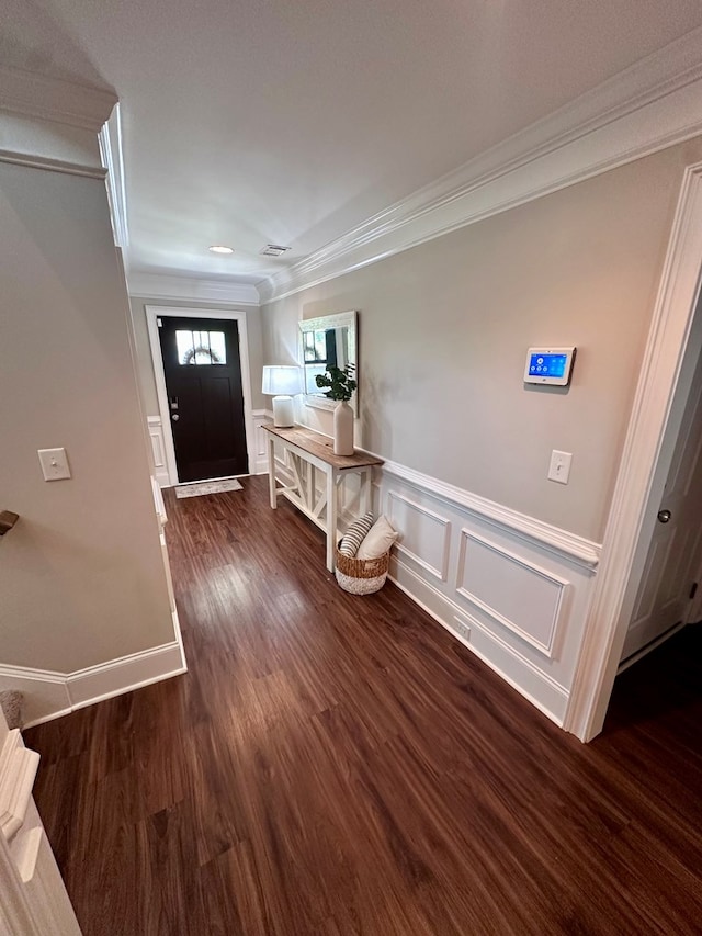 foyer entrance featuring a wainscoted wall, ornamental molding, a decorative wall, and wood finished floors
