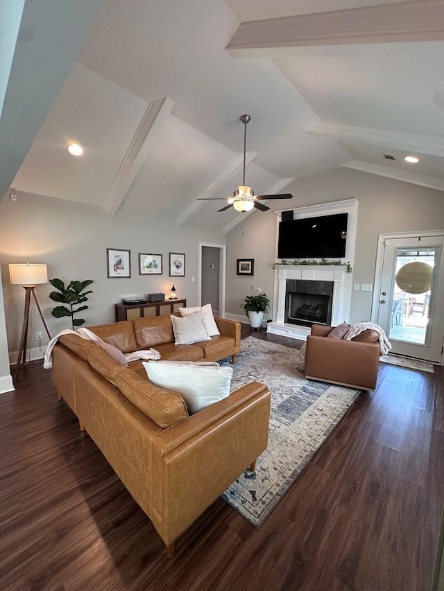 living area with a ceiling fan, dark wood-style flooring, a tile fireplace, baseboards, and vaulted ceiling with beams