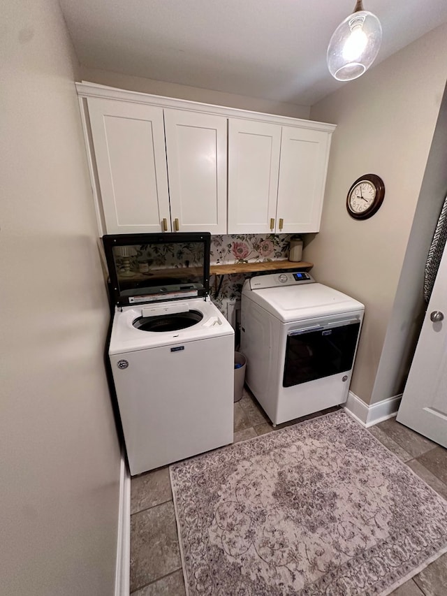 washroom featuring baseboards, cabinet space, and independent washer and dryer