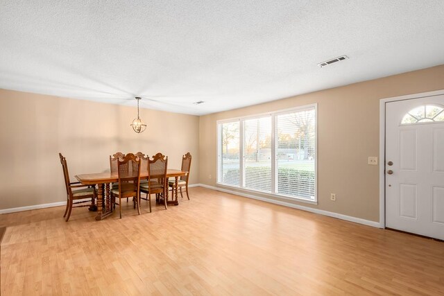 dining space featuring a textured ceiling, light wood-style flooring, visible vents, and baseboards