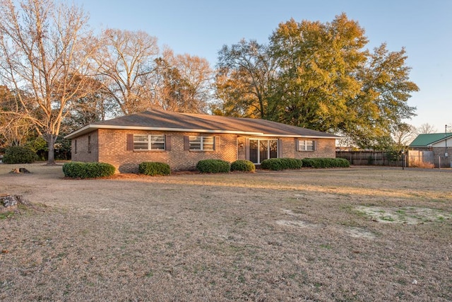 ranch-style home with brick siding, fence, and a front lawn