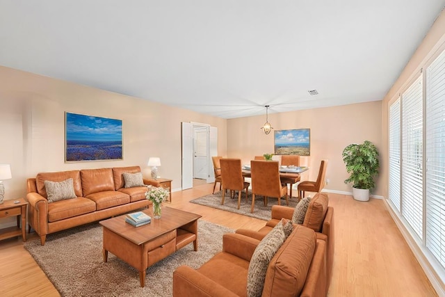 living room with visible vents, light wood-style flooring, and baseboards