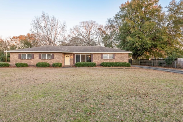 ranch-style home with brick siding, fence, and a front yard