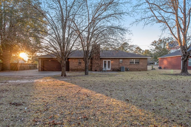 ranch-style house featuring an attached garage, central air condition unit, brick siding, fence, and driveway