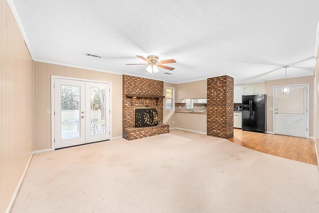 unfurnished living room featuring light carpet, french doors, a brick fireplace, and crown molding