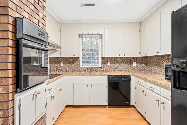 kitchen with light wood finished floors, visible vents, ornamental molding, black appliances, and a sink