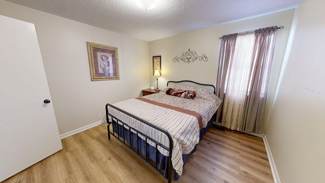 bedroom featuring a textured ceiling and light hardwood / wood-style flooring