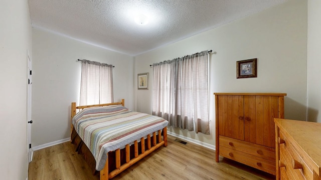 bedroom with a textured ceiling and light hardwood / wood-style flooring