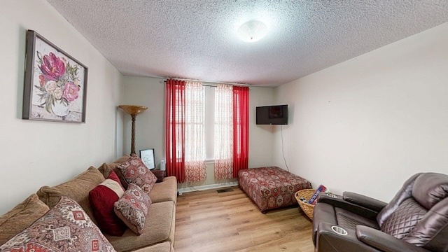 living room with a textured ceiling and light wood-type flooring