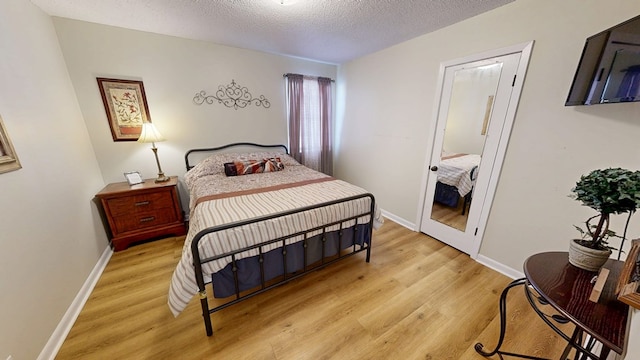 bedroom featuring light hardwood / wood-style flooring and a textured ceiling