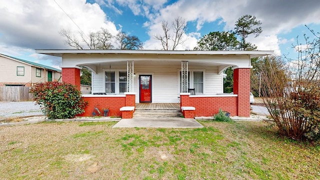 bungalow-style home featuring covered porch and a front lawn