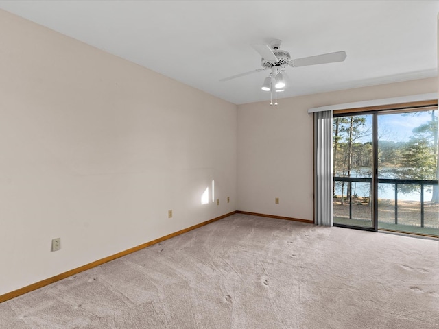 empty room featuring light colored carpet, ceiling fan, and a water view