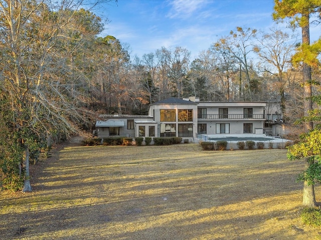 view of front of home with a balcony, a sunroom, and a front yard