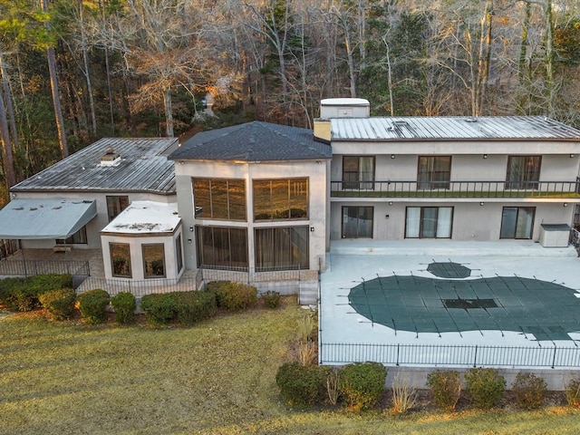 rear view of house featuring a patio, a covered pool, and a lawn