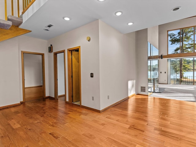 unfurnished room with a towering ceiling and light hardwood / wood-style floors