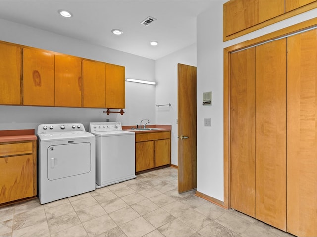 clothes washing area featuring cabinets, sink, and washer and dryer