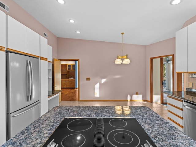 kitchen featuring hanging light fixtures, dark stone countertops, light tile patterned floors, appliances with stainless steel finishes, and white cabinets