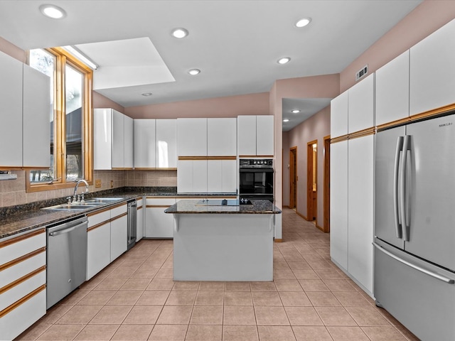 kitchen with sink, black appliances, dark stone countertops, a kitchen island, and white cabinets