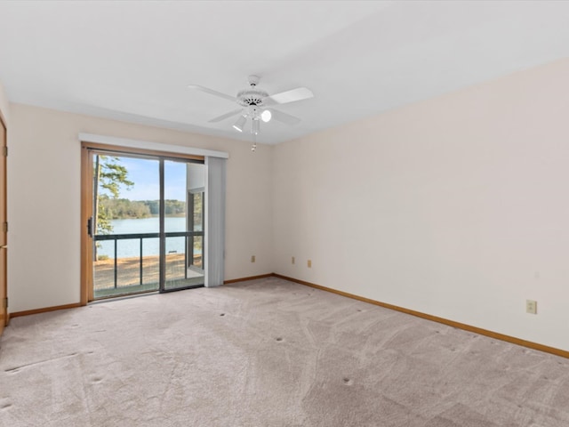 unfurnished room with a water view, light colored carpet, and ceiling fan