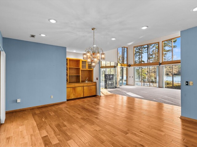 unfurnished living room featuring a notable chandelier and light wood-type flooring