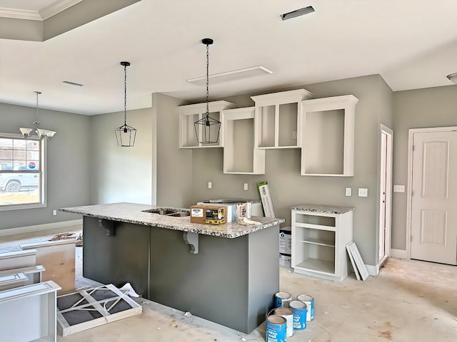 kitchen featuring a kitchen bar, light stone countertops, a kitchen island with sink, and hanging light fixtures