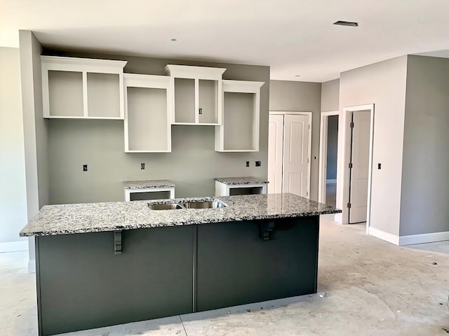 kitchen featuring stone countertops, a kitchen breakfast bar, sink, and a large island with sink