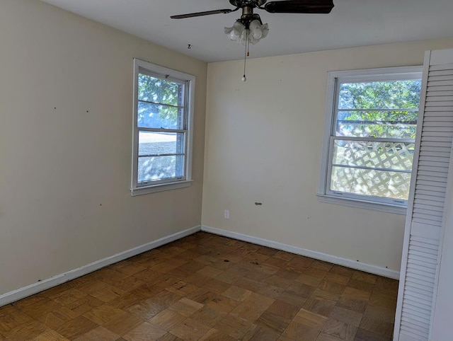 unfurnished room with dark parquet flooring and ceiling fan