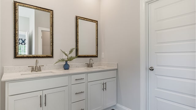 full bath with double vanity, baseboards, and a sink