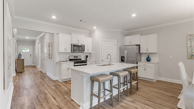 kitchen with white cabinets, an island with sink, appliances with stainless steel finishes, light countertops, and a sink