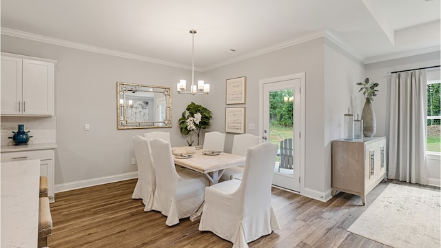 dining space featuring ornamental molding, light wood-type flooring, a notable chandelier, and baseboards