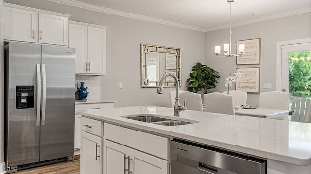 kitchen featuring stainless steel appliances, an island with sink, a sink, and white cabinetry