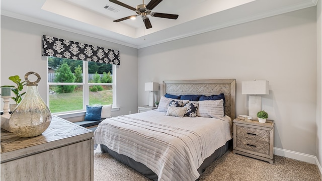 carpeted bedroom featuring ornamental molding, a tray ceiling, visible vents, and baseboards