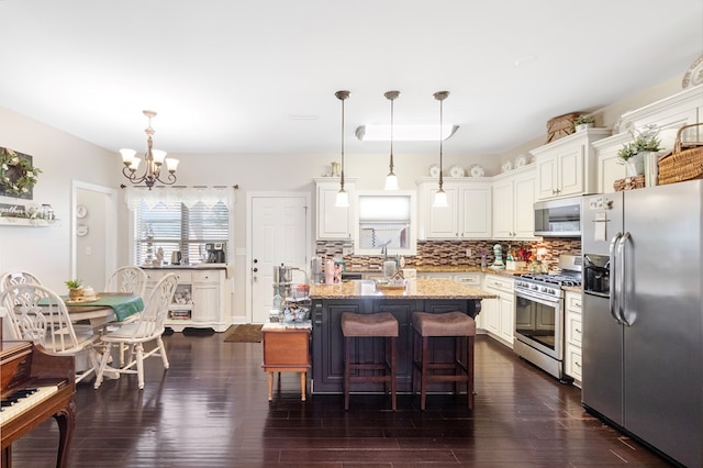 kitchen featuring pendant lighting, a center island, stainless steel appliances, and light stone counters