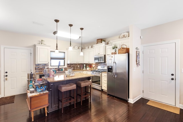 kitchen featuring light stone counters, dark hardwood / wood-style flooring, decorative light fixtures, a kitchen island, and appliances with stainless steel finishes