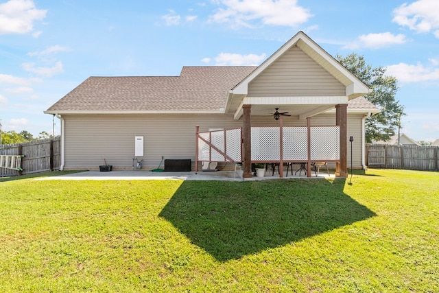 rear view of house featuring ceiling fan and a yard