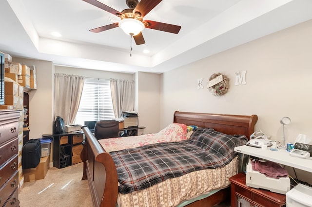 carpeted bedroom featuring ceiling fan and a tray ceiling